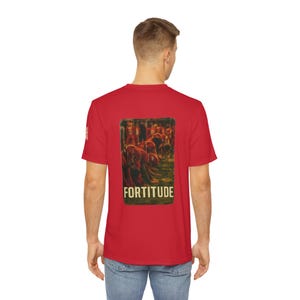 May include: A red t-shirt featuring a rectangular graphic on the back with the word "FORTITUDE" in white. The graphic depicts a group of people in a field. The shirt is short-sleeved.