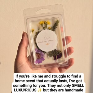 Può includere: Un contenitore in plastica trasparente contenente cere profumate bianche con elementi botanici essiccati gialli, viola e verdi. Un'etichetta bianca circolare al centro riporta il testo Charleys Candles. Sono presenti sovrapposizioni di testo.