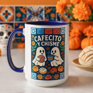 May include: White ceramic mug with a blue handle and rim, featuring the text "CAFECITO Y CHISME" and illustrations of two ghosts, coffee, and pastries. The mug is decorated with floral and geometric patterns, and is set against a colorful background.