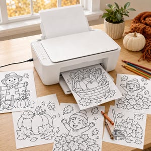 May include: A white inkjet printer with a stack of blank paper in the rear tray and a printed coloring page featuring a basket of autumn produce emerging from the front. Several other fall-themed coloring sheets and two crayons are nearby.