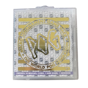 Può includere: Una custodia di plastica trasparente contenente un set di giochi POG. Il set include milkcaps, kinis, un tabellone e una guida. La custodia ha un design in lamina d'oro con le scritte "MICRO TOURNAMENT GAME FEDERATION" e "THE WORLD POG".