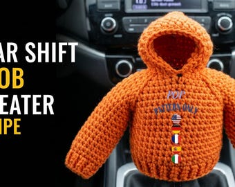 May include: An orange crocheted gear shift knob sweater with a hood. The text GEAR SHIFT KNOB SWEATER RECIPE is on the left. The sweater features the text POP PATTERN ONLY and a vertical row of five circular flag icons representing the USA, Germany, France, Spain, and Italy.
