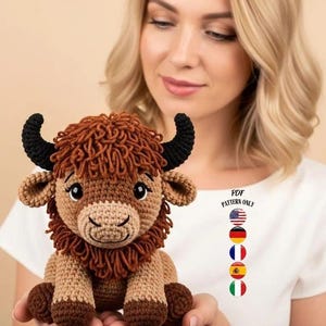 Puede incluir: Peluche de bisonte de ganchillo, con hilo marrón y beige, cuernos negros y una melena esponjosa. El bisonte se sostiene frente a una persona que lleva una camiseta blanca con el texto "PDF PATTERN ONLY" y banderas.