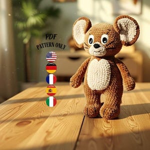 Könnte beinhalten: Ein gehäkeltes braunes Mausspielzeug mit großen Ohren und einem weißen Bauch, das auf einem Holztisch steht. Das Spielzeug hat schwarze Augen und eine weiße Schnauze. Der Text auf dem Bild lautet "PDF PATTERN ONLY".
