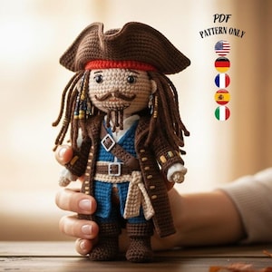 Könnte beinhalten: Gehäkelte Piratenpuppe mit braunem Hut, Mantel und Stiefeln, rotem Bandana und blauer Weste. Die Puppe hat lange braune Haare und einen Schnurrbart. Der Text "PDF PATTERN ONLY" ist sichtbar.