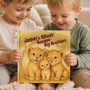 Pode incluir: Um livro infantil de capa dura com uma capa bege apresentando uma ilustração castanha de três filhotes de leão sentados sob uma árvore. O texto na capa diz James & Oliver Become Big Brothers em letras castanhas acima dos filhotes.