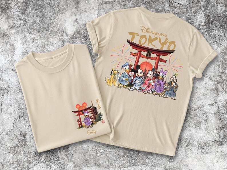 May include: Two beige t-shirts with Japanese-themed Disney graphics. One shirt features a front graphic of a red torii gate and a Disney character. The other shirt has a back graphic of Disney characters in traditional Japanese attire, with the text "Disneyland TOKYO".