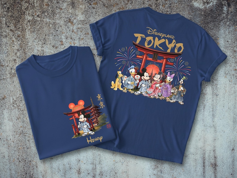 May include: Two navy blue t-shirts with a Disneyland Tokyo theme. One shirt features Mickey Mouse in a kimono with a Japanese pagoda. The other shirt has a graphic of Disney characters in kimonos in front of a Japanese gate.