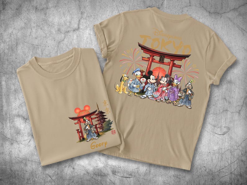 May include: Two tan t-shirts with Japanese-themed Disney character graphics. One shirt features Mickey, Minnie, Donald, Daisy, and Goofy in traditional Japanese attire. The other shirt has a similar design with a pagoda and the word "Goofy".