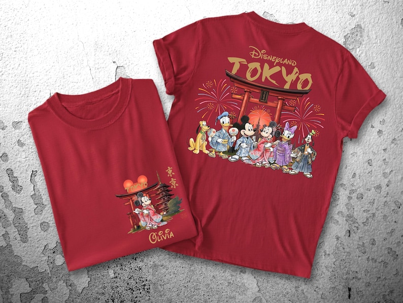 May include: Two red t-shirts. One features a graphic of Mickey Mouse in traditional Japanese attire with the text "Olivia". The other shirt has "Disneyland TOKYO" and Disney characters in Japanese clothing.