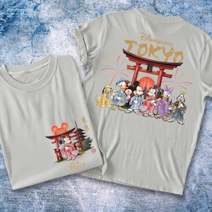 May include: Two light gray t-shirts with Japanese-themed Disney character graphics. One shirt features Mickey Mouse in a kimono, the other has a group of characters in front of a Torii gate with "Disneyland Tokyo" text.