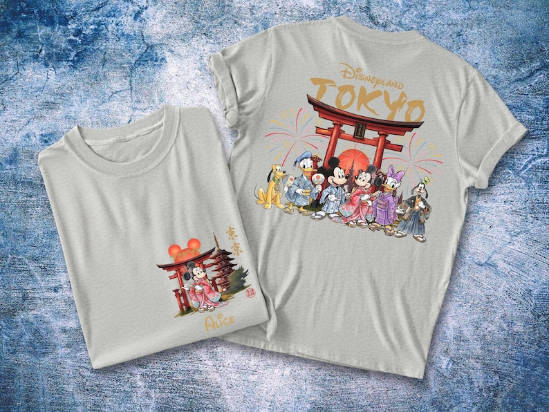 May include: Two light gray t-shirts with Japanese-themed Disney character graphics. One shirt features Mickey Mouse in a kimono, the other has a group of characters in front of a Torii gate with "Disneyland Tokyo" text.