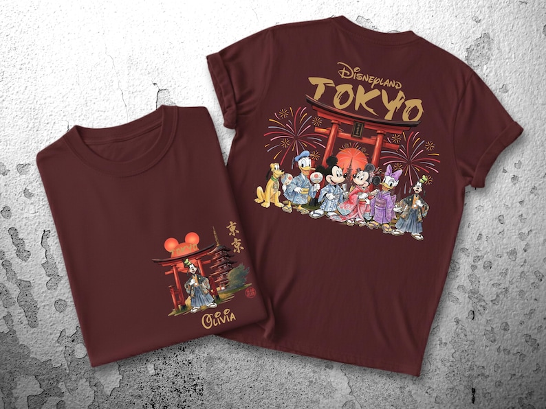 May include: Two maroon t-shirts with Japanese-themed Disney designs. One shirt features a front graphic of a pagoda and Mickey Mouse ears, with the name "Olivia." The other shirt has "Disneyland TOKYO" and Disney characters in traditional Japanese attire.