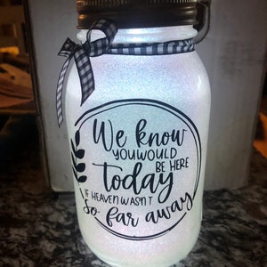 May include: A white mason jar with a black and white checkered ribbon around the lid. The jar is filled with glitter and has a black vinyl decal with the text "We know you would be here today if heaven wasn't so far away."