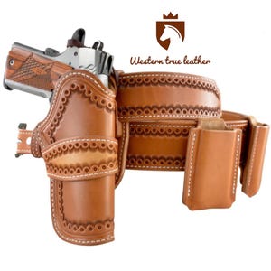 Puede incluir: Un juego de cinturón y funda de cuero marrón con costuras decorativas y una funda para cargador a juego. El juego incluye una pistola plateada. El logotipo "Western true leather" es visible.