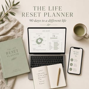 May include: A lifestyle image featuring a laptop displaying a life audit, a journal, a smartphone, and a mug. The text on the journal reads "The Life Reset Planner" and "90 days to a different life." A gold pen rests on the open journal with handwritten goals.
