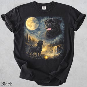 May include: A black t-shirt featuring a graphic print of a black pug standing in a forest landscape at night under a large full moon. The design includes a second, larger portrait of a black pug head with its tongue out, positioned above the forest.