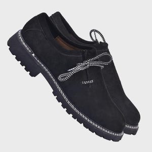 Puede incluir: Zapatos de ante negro con suelas gruesas. Los zapatos tienen costuras blancas alrededor de las suelas y cordones con estampado blanco y negro. Diseño clásico y robusto, adecuado para diversas ocasiones.