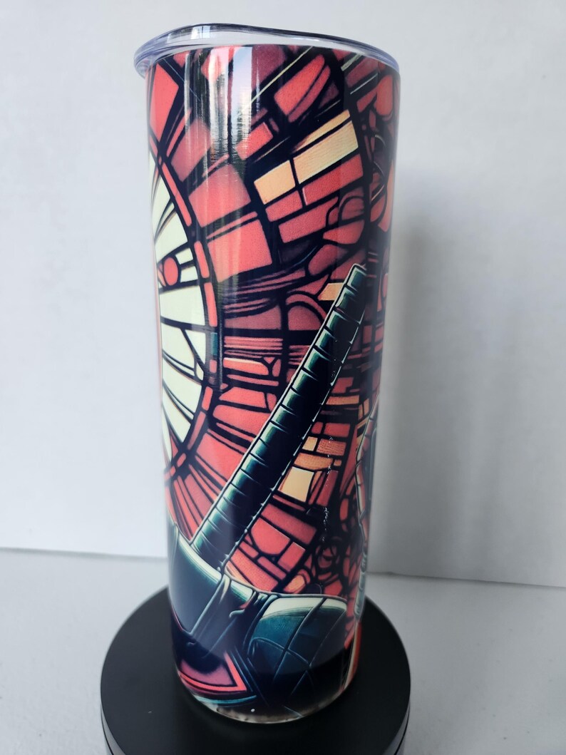 Puede incluir: Un vaso alto y aislado con un dise&ntilde;o de vidriera en tonos rojos, naranjas y negros. El vaso tiene una tapa transparente y una base negra. El dise&ntilde;o presenta formas y l&iacute;neas geom&eacute;tricas.