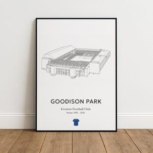 May include: A framed print featuring a detailed line drawing of Goodison Park, the home of Everton Football Club. The print includes the text "GOODISON PARK" and "Home 1892-2025", along with a blue jersey icon. The artwork is in black and white.