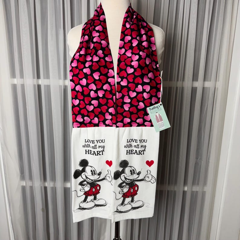 May include: A Valentine's Day themed kitchen towel set. The top scarf is black with pink and red hearts. The bottom towels are white with a Mickey Mouse graphic and the text "LOVE YOU with all my HEART".