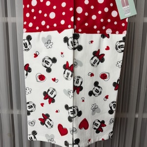 May include: A red and white polka dot and Minnie Mouse patterned kitchen towel. The top section is red with white polka dots. The bottom section is white with Minnie Mouse, hearts, and flower graphics.