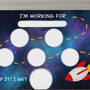 以下が含まれることがあります： 宇宙をテーマにしたご褒美チャート。背景は濃い青と紫の銀河です。チャートには、ご褒美用の空白、6つの円、ロケットがあります。「I'm working for」と「I did it! I get」というテキストがあります。