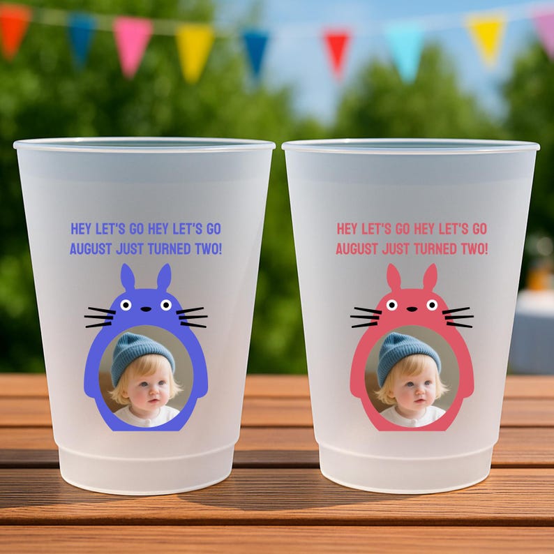 May include: Two white plastic cups with a frosted finish. Each cup features a cartoon character frame in blue and pink, with a child's photo inside. The text "HEY LET'S GO HEY LET'S GO AUGUST JUST TURNED TWO!" is printed above the character.