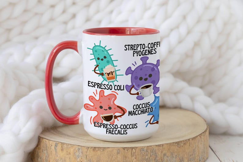 May include: White ceramic coffee mug with a red interior and handle. The mug features cartoon illustrations of microbes with coffee cups and the phrases "Espresso Coli," "Strepto-Coffi Pyogenes," and "Espresso-cocus Faecalis."