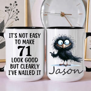 May include: A white ceramic mug with a black handle and rim, featuring the black text 'IT'S NOT EASY TO MAKE 71 LOOK GOOD BUT CLEARLY I'VE NAILED IT' on one side and a cartoon black bird with the name 'Jason' printed in black script below it.