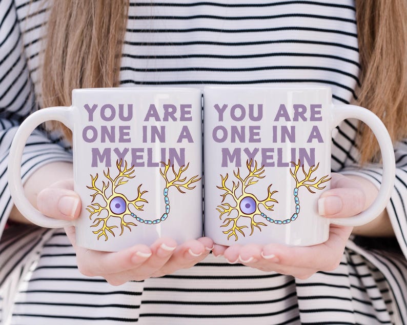 May include: Two white ceramic mugs with the text "YOU ARE ONE IN A MYELIN" in purple. Each mug features a yellow and blue neuron illustration. The mugs are held by a person.
