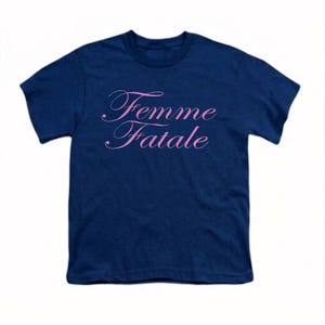以下が含まれることがあります： 前面にピンク色の筆記体で「Femme Fatale」と書かれたネイビーブルーのTシャツ。テキストは筆記体フォントです。Tシャツは無地で、半袖です。