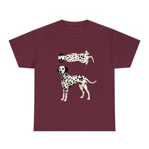 May include: A maroon short-sleeved t-shirt featuring a graphic print of a Dalmatian dog. The design includes two illustrations of the dog: one standing in profile facing left and another positioned above it, shown from a top-down perspective.