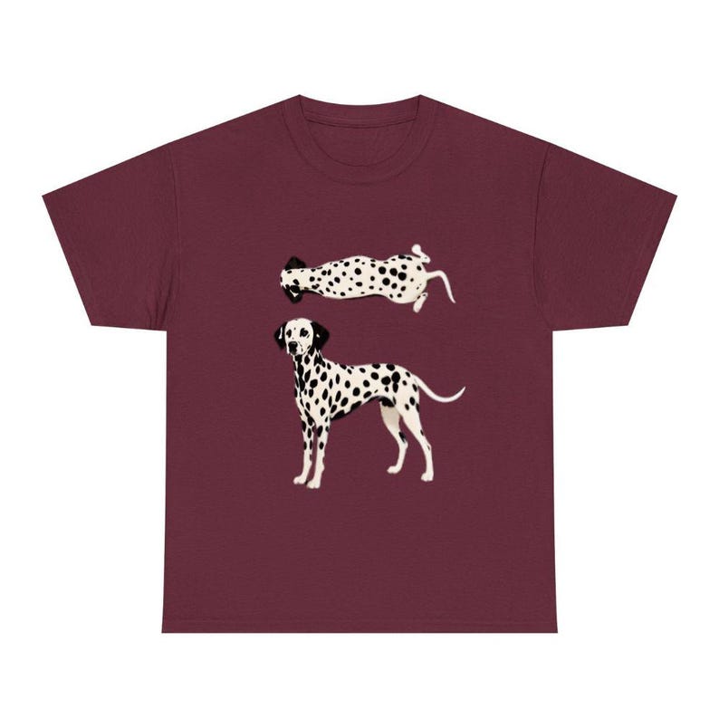 May include: A maroon short-sleeved t-shirt featuring a graphic print of a Dalmatian dog. The design includes two illustrations of the dog: one standing in profile facing left and another positioned above it, shown from a top-down perspective.