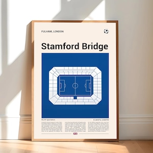 May include: A framed poster featuring a blue and white illustration of Stamford Bridge stadium. The poster includes the text "FULHAM, LONDON" and "Stamford Bridge" in bold letters. The poster is leaning against a white wall and a wooden floor.