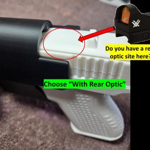 May include: A black holster with a white interior, designed to accommodate a firearm. The image includes a red dot optic sight and text that reads "Do you have a rear optic site here?" and "Choose 'With Rear Optic'".