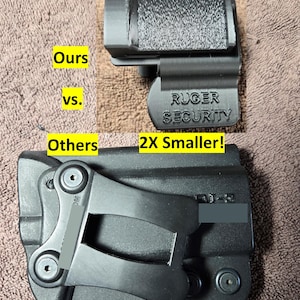Op de afbeelding: Zwarte plastic holsterclip met de tekst "RUGER SECURITY" en een vergelijking met een grotere holster. De tekst "Ours vs. Others" en "2X Smaller!" zijn ook zichtbaar.