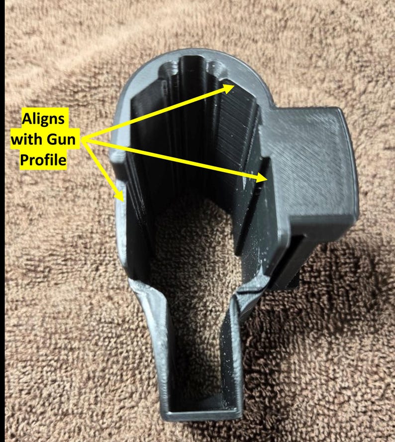 Op de afbeelding: Een zwart, 3D-geprint object met een holle binnenkant en een rechthoekige vorm. De tekst "Aligns with Gun Profile" is zichtbaar. Het object lijkt ontworpen om in een specifiek profiel te passen.