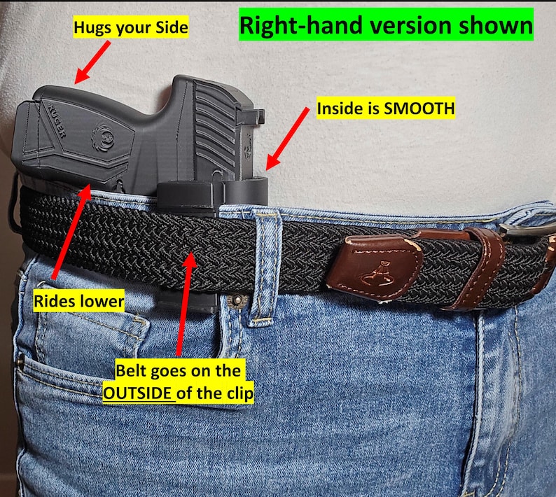 May include: A black handgun holster attached to a black woven belt worn with blue jeans. The holster is designed to ride lower and hug the side. The belt goes on the outside of the clip. The inside of the holster is smooth.