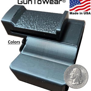 May include: A black holster with a textured surface and a belt clip attachment. The text GunToWear is visible at the top, along with an American flag icon and the text Made in USA. A United States quarter dollar coin is placed next to the holster.