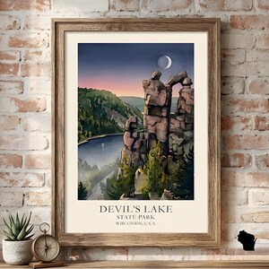 May include: Framed print of Devil's Lake State Park in Wisconsin, USA. The artwork depicts a scenic landscape with rock formations, a lake, and a crescent moon in the night sky. The print is in a wooden frame.
