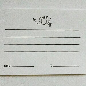 May include: A blank white card with a black pumpkin and vine design. The card has lines for writing and says "FROM" and "TO" at the bottom.