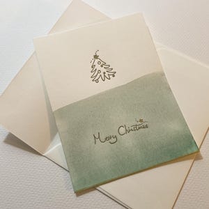 Kerstkaart boekdruk: kerstboom "Merry Christmas" gekleurd met waterverf. met cadeau, kerstkaart
