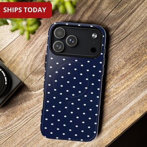 Puede incluir: Una funda de teléfono azul marino con un patrón de lunares blancos. La funda tiene un recorte para la cámara y un diseño circular en la parte posterior. Las palabras "SHIPS TODAY" están en un rectángulo rojo.