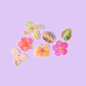 May include: A collection of seven individual stickers featuring floral and botanical designs. The set includes two pink flowers, one orange flower, and four green and pink leaves, all finished with a holographic glitter effect that catches light.
