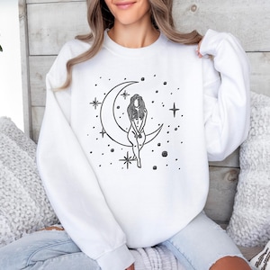 May include: A white ceramic mug with a black handle and the text "But First, Coffee" in a bold, black font. The mug is set against a neutral background, highlighting its simple design.