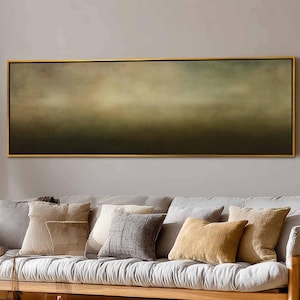May include: An abstract landscape painting in a gold frame. The artwork displays a gradient of colours, shifting from dark green at the bottom to lighter shades of green and yellow at the top. The painting hangs above a grey sofa with decorative cushions.