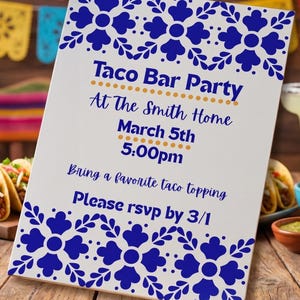 Peut inclure: Un panneau rectangulaire blanc avec des motifs floraux bleus en haut et en bas. Le texte indique : Taco Bar Party, At The Smith Home, March 5th, 5:00pm, Bring a favorite taco topping, Please rsvp by 3/1. Le panneau est sur une table en bois.