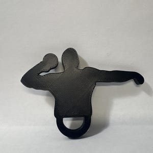 May include: A black, 3D-printed silhouette of a person throwing a shot put. The figure is in mid-throw, with one arm extended and the other bent, holding the shot put. A ring is at the bottom of the figure.