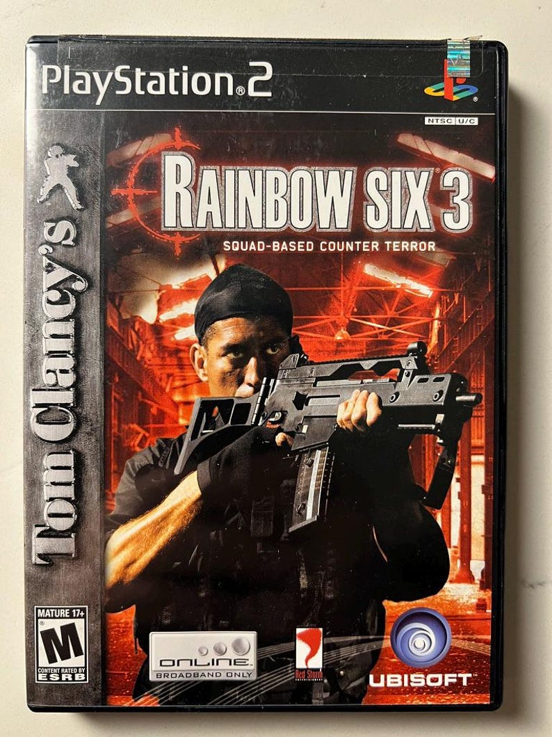 Puede incluir: Caja de videojuego de PlayStation 2 para "Tom Clancy's Rainbow Six 3: Squad-Based Counter Terror". La portada muestra a un hombre con un arma. El t&iacute;tulo del juego es prominente. La caja tiene una clasificaci&oacute;n ESRB Mature 17+.